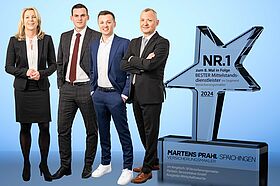 Vier Martens & Prahl Mitarbeiter stehen neben der Auszeichnung für den besten Mittelstandsdienstleister.